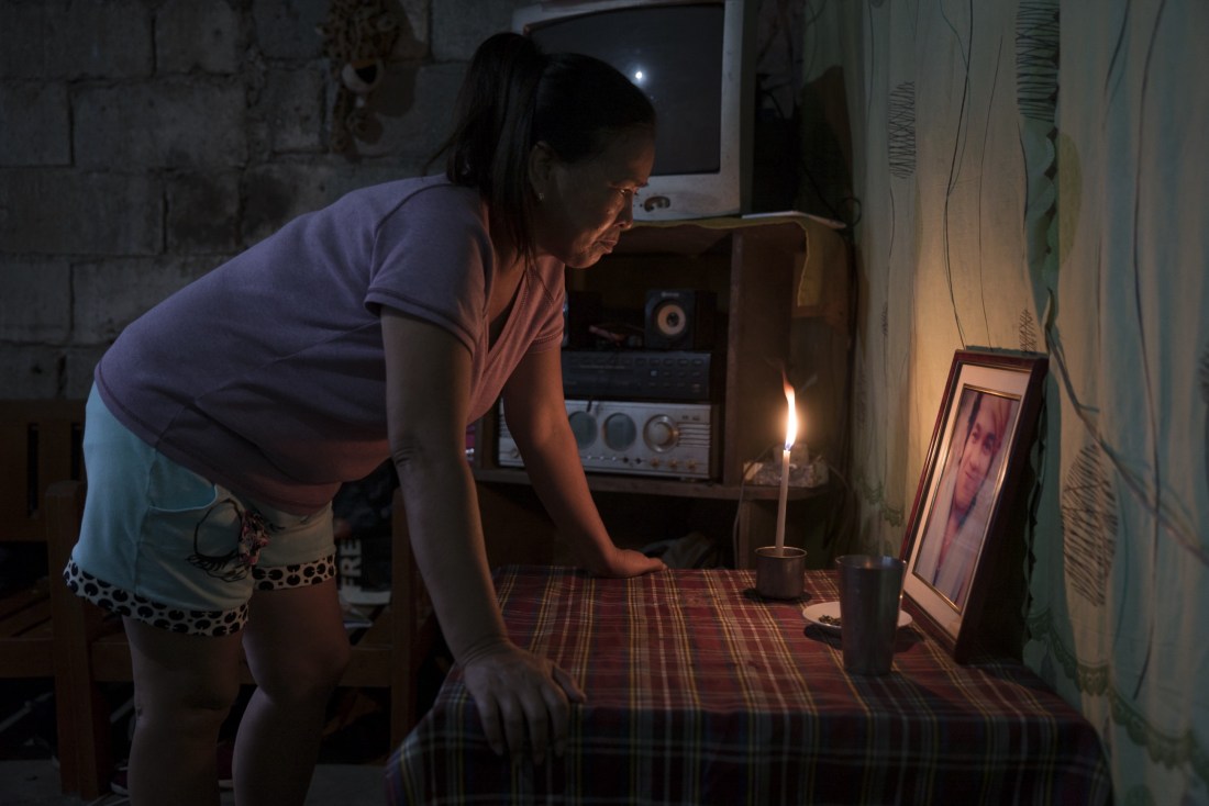 Julie lights a candle at dusk for her son, who was killed by masked policemen last June—one of thousands of who have been killed in Duterte’s violent campaign against drugs. Masked policemen entered their home in the middle of the night and killed her son. Photo: Ed Ou